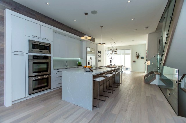 Custom kitchen with double wall ovens and stone waterfall island