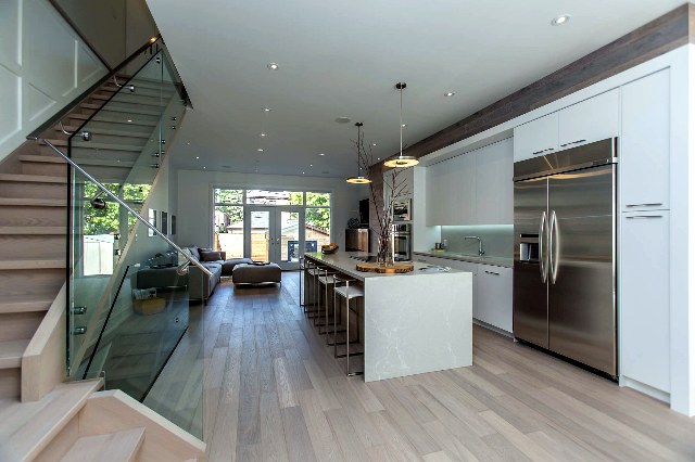 Open-concept main-floor renovation with kitchen, living area and glass-railing staircase