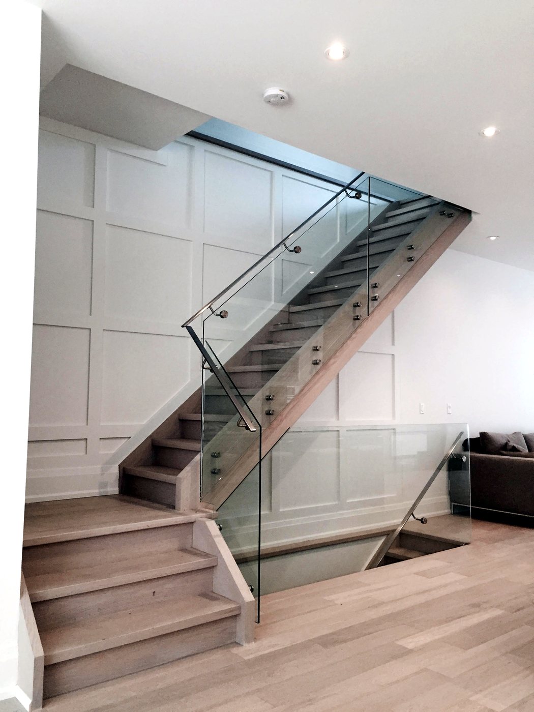 Floating staircase with frameless glass railing and wood treads